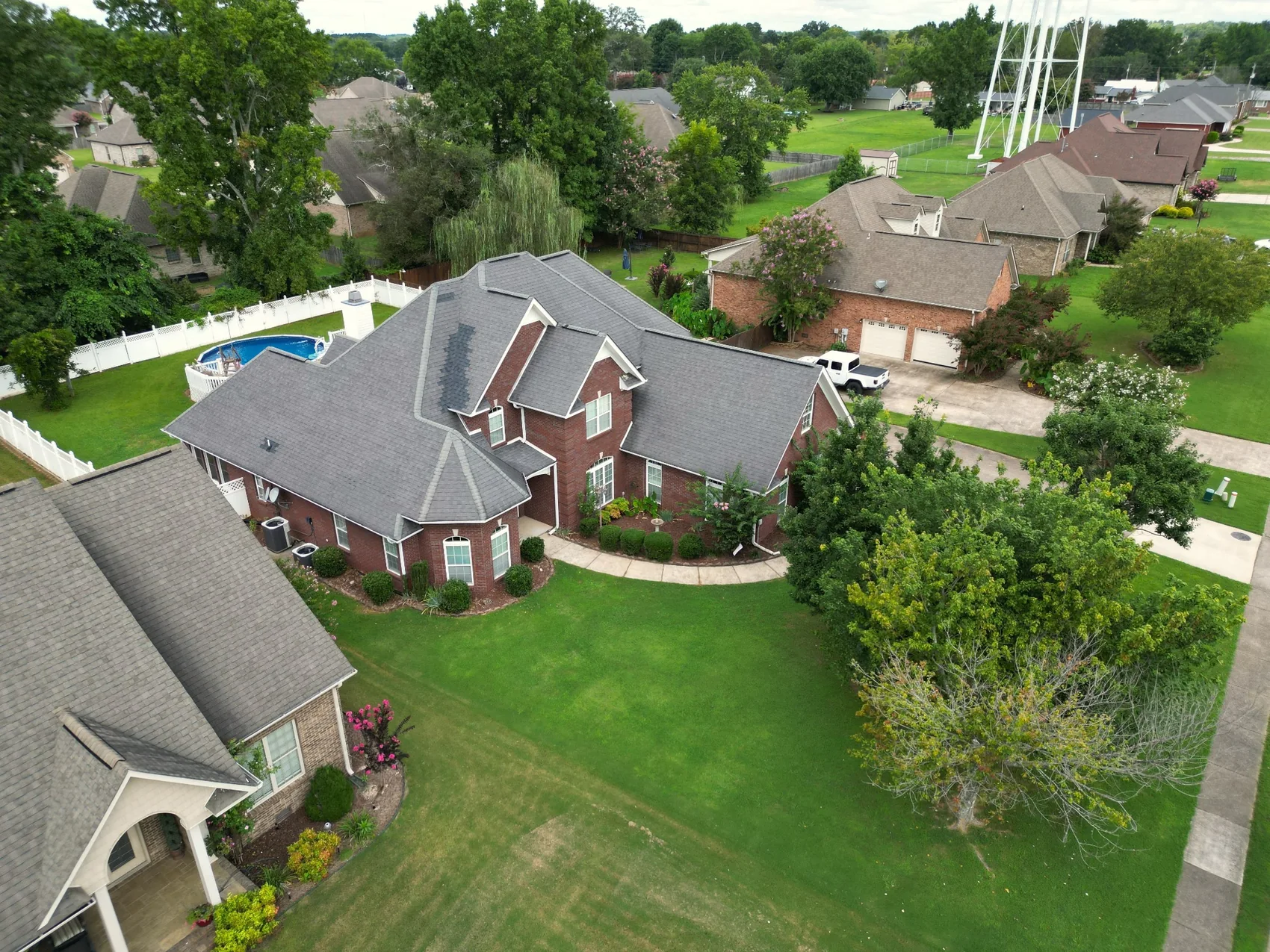 Elevated drone view of a brick home and landscaped grounds