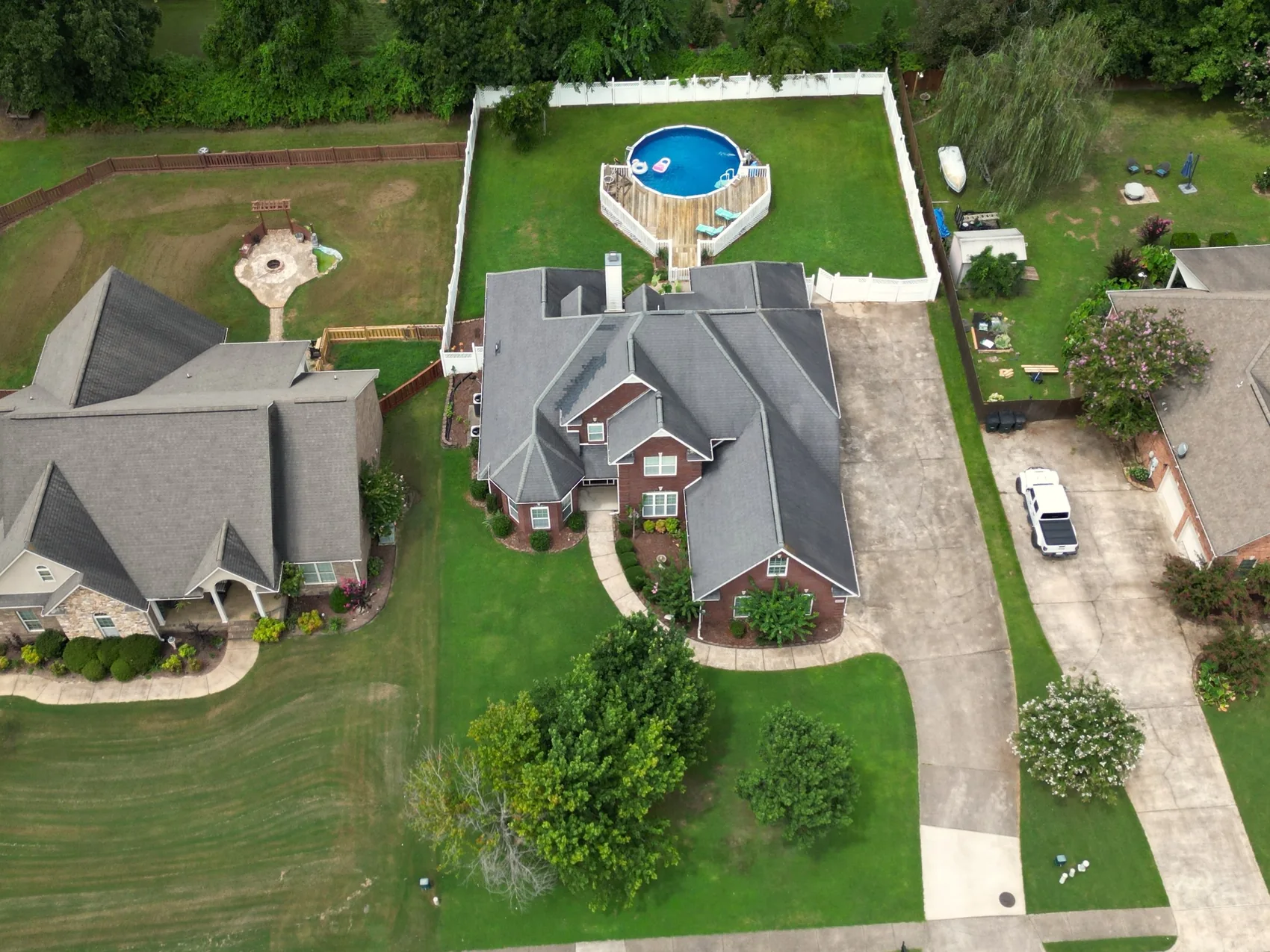 Overhead aerial of brick home with backyard pool and driveway